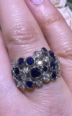 a close up of a person's hand wearing a ring with blue and white stones