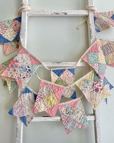 an old ladder is decorated with colorful quilts and bunting strips for the decoration