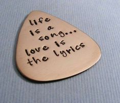 a guitar pick with the words life is a song love is the music on it