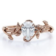 a rose gold ring with an oval cut diamond in the center and leaves on each band