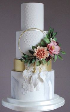 a white and gold wedding cake with flowers on top