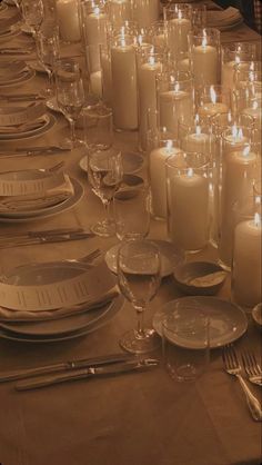 a long table is set with candles and place settings for dinner guests to sit at