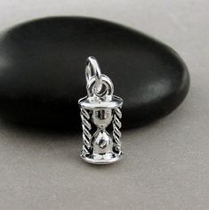 "This Tiny Hourglass Charm comes with a silver jump-ring as pictured. Please note that photo is not to scale and may appear larger to show detail. Refer to exact measurements below. Additional attachments (lobster clasp, large-hole bead, necklace chains) are available from the charm-attachments drop-down menu.  For a visual example of the different attachments and what each one is best suited for, scroll through the photos until you see the example photo or visit https://etsy.me/2BY7DAW for detailed information.    { DETAILS } ★ Material: Pewter  ★ Finish Color: Silver  ★ Measurements: 1/4\" x 1/2\" ★ Dimensions: 3-Dimensional ★ Made in the USA { SIMILAR ITEMS }  More time themed items available from my shop: https://www.etsy.com/shop/treasuredcharms/search?search_query=time { GIFT OPTIONS Hourglass Charm, Egg Timer, Sand Timer, Sand Timers, Pandora Beads, Gift Of Time, Large Hole Beads, Pandora Bracelet, Beaded Dangles