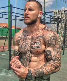 a man with tattoos on his chest wearing headphones