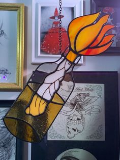 a stained glass lamp hanging from a chain in a room with pictures on the wall