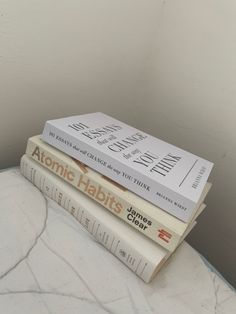 three books stacked on top of each other in front of a white wall and floor