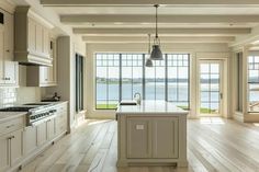 a large kitchen with white cabinets and an island in front of a window overlooking the water