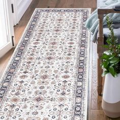 a large white rug on the floor next to a chair and potted green plant