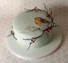 a white cake with a bird on top and red berries around the edges is sitting on a table