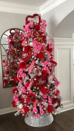 a red and silver christmas tree in a living room with ornaments on the base,