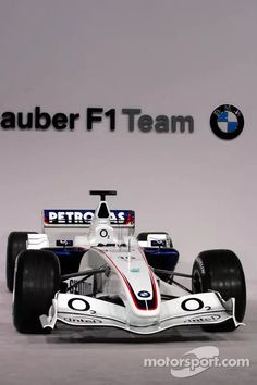 the new bmw team car is shown in front of a wall with an ad for its logo