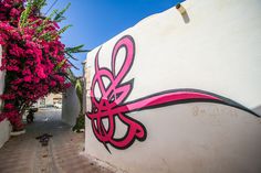 graffiti on the side of a white building with pink flowers growing out of it's sides