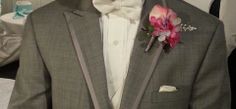 a man in a tuxedo with a pink flower on his lapel and bow tie