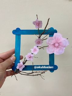 a hand holding up a blue frame with pink flowers on it