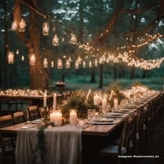 an outdoor dinner table set with candles, greenery and hanging mason - jar lights