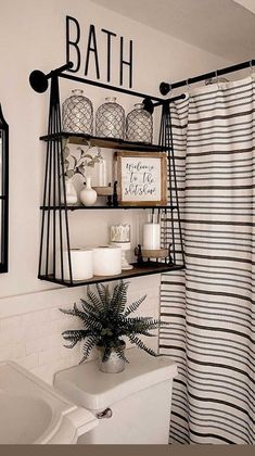 a bathroom with black and white decor on the shelves above the bathtub is decorated with greenery