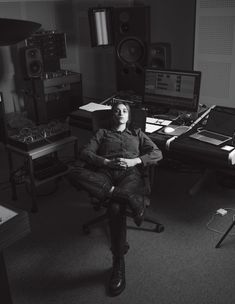 a woman sitting in a chair next to a desk with several sound equipment on it