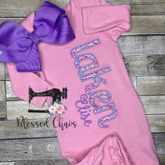 "This gorgeous floral pink and purple baby gown is a perfect baby shower gift or coming home outfit for the new baby! The baby gown is personalized with baby's name down the side in an appliqué font as well as a stitched middle name.  The fabrics in the listing can be changed, contact me for more fabric choices. A middle name can be stitched under the first name if desired.  This listing can be for the baby gown alone or the baby gown with a knot cap to match. The knot cap can be personalized with baby's name.  There are several colors of the baby gown, including: bubble gum pink (ruffle bottom), white (plain & ruffle), black, grey, light blue, navy, red, and mint. All colors have a knot cap to match. Baby Gowns: *6.0 - 6.5 oz. 100% Ring spun combed cotton *1/2\" elastic on the bottom *20\ Gift Fitted Pink Dress, Fitted Pink Dress For Gifts, Pink Fitted Dress For Gift, Fitted Pink Dress As Gift, Pink Fitted Dress As A Gift, Baby Gown With Name, Personalized Pink Onesie For Birthday, Matching Sister Shirts, Fitted Pink T-shirt With Name Print