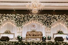 the stage is decorated with white flowers and greenery