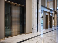 an elevator in a building with marble floors and glass doors that lead to the elevators