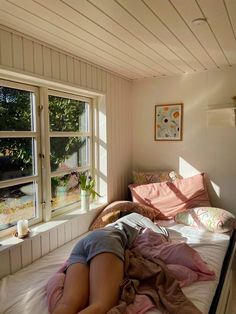 a woman laying on top of a bed next to a window