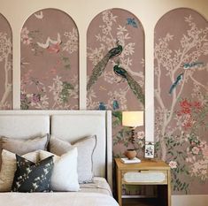 a bedroom decorated in pink and white with peacocks on the wall next to it