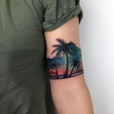 a person with a palm tree tattoo on their arm and the sun setting behind them