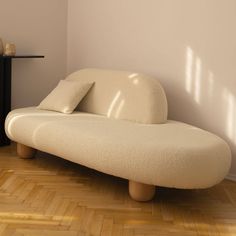 a white couch sitting on top of a hard wood floor next to a shelf with vases