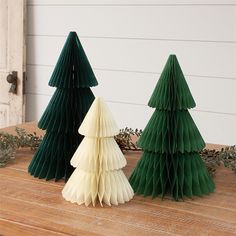 three paper christmas trees sitting on top of a wooden table