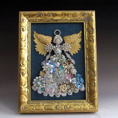 an ornate gold frame holds a decorative angel ornament in the shape of a christmas tree