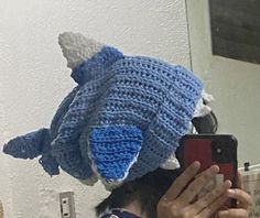 a person taking a selfie in front of a mirror wearing a crocheted hat