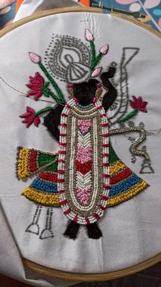 a close up of a embroidery on a piece of cloth with an embroidered figure in the center