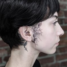 a woman with tattoos on her face and behind her ear