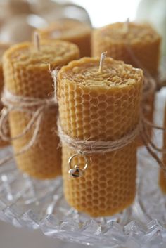 four bees are wrapped in wax and tied with twine on a glass platter