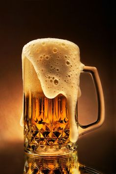 a glass mug filled with beer sitting on top of a table