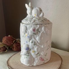 a white ceramic container sitting on top of a tree stump