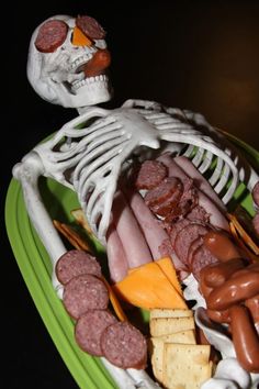 a skeleton is holding a platter with sausages, hot dogs and cheese