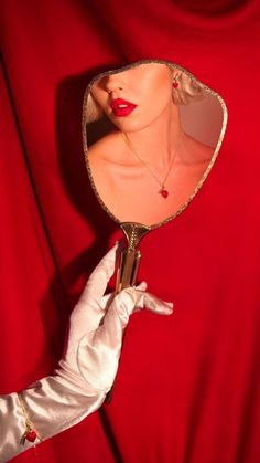 a woman's hand holding a mirror with a mannequin head in it