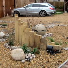 a car is parked in the driveway next to some rocks and plants on the ground