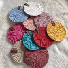 multicolored braided placemats with wooden handles on a white bed sheet