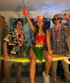 two men and a woman are posing for a photo with a surfboard in front of them