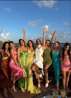 a group of women standing next to each other on top of a wooden floor near the ocean