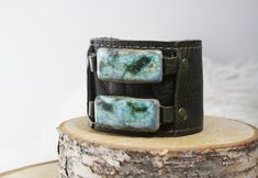 Ceramic mystic leather cuff. Olive green leather, with buckle closure to fit most.  You've arrived at Dandy Outlet! This handcrafted ceramic piece of jewelry is handmade and one-of-a-kind, and the piece pictured is the piece you will receive. As with outlet shopping, each item is imperfect. It may have a drip or a hole, or the glaze may not have turned out as intended. Your win! Outlet prices are 25-50% off regular store and website prices.  Outlet pieces are final sale only, and stock is limite Handmade Earthy Leather Bracelet Gift, Handmade Earthy Leather Bracelet For Gift, Earthy Handmade Leather Bracelet Gift, Earthy Handmade Leather Bracelet For Gift, Handmade Green Leather Bracelet, Adjustable Green Cuff Bracelet With Patina, Handmade Adjustable Rectangular Leather Bracelet, Handcrafted Ceramics, Leather Cuffs