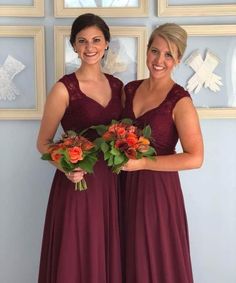 two women in long dresses standing next to each other with flowers on their bouquets