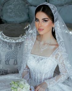 a woman in a white wedding dress sitting on a couch with a bouquet of flowers