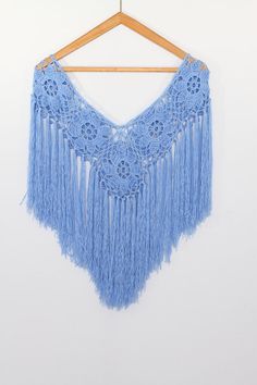 a blue crochet doily hanging from a wooden hanger on a white wall