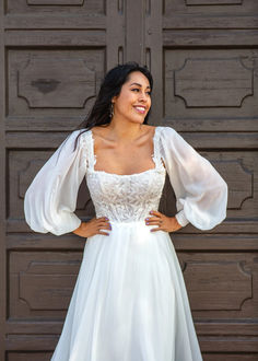 a woman wearing a white dress standing in front of a wooden door