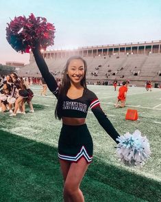 a cheerleader is standing on the field with her pom poms in hand