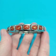 a person holding a metal ring with red and gold designs on it's sides