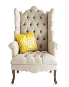 a white chair with a yellow pillow on it's back and an arm rest